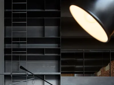 A modern minimalist kitchen with metal shelves and a wooden countertop.