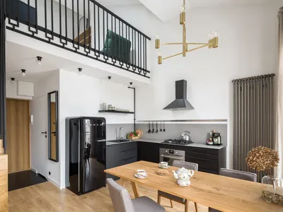 A modern minimalist kitchen with black appliances, white countertops, wooden furniture, and metallic accents.