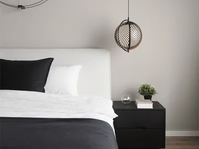 A minimalist bedroom featuring a black and white color scheme with a bed, black headboard, and white bedding, along with a mo