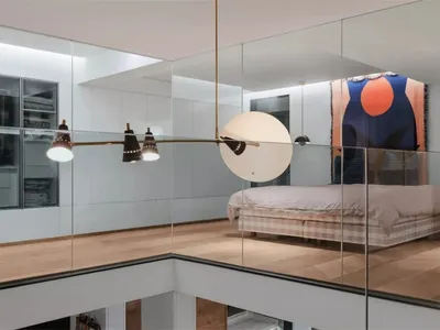 A modern minimalist bedroom with a glass wall, showcasing a single bed and minimal decor.