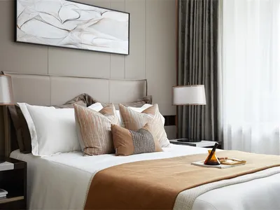 Modern bedroom featuring a brown and white lampshade and black and gray striped pillows.