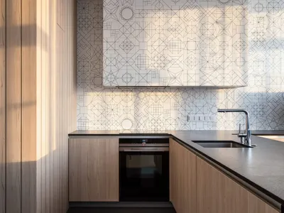 Modern kitchen with wooden cabinets and geometric tile backsplash.