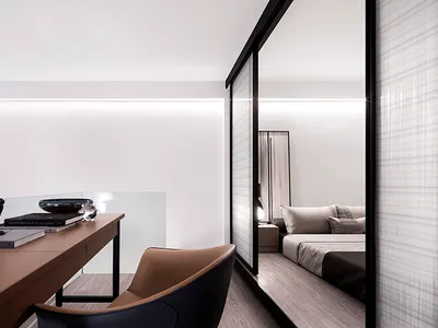 A modern minimalist bedroom featuring transparent glass walls and a sleek desk.