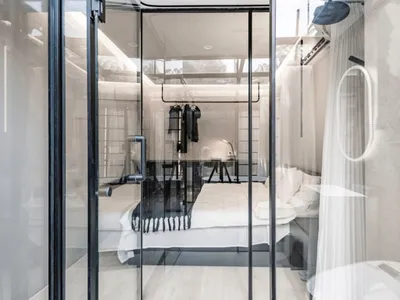 Modern hotel room with glass walls and minimalist decor.