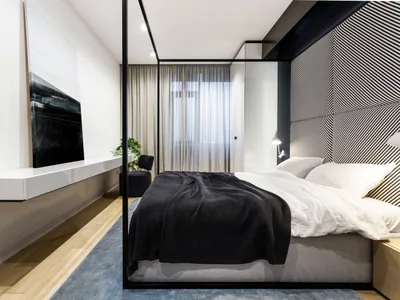 Modern minimalist bedroom featuring a high-tech design with fabric bedding, wooden flooring, and glass elements.