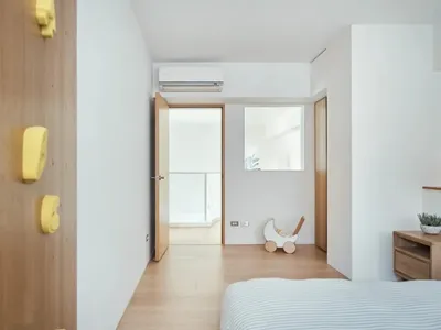 Minimalist bedroom with wooden furniture and a white air conditioner unit mounted on the wall.
