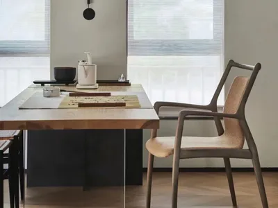 A modern home office with wooden furniture, a minimalist desk, and a hanging light fixture.