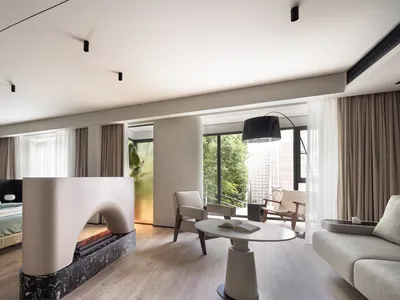 Modern minimalist bedroom with white bed, fireplace, and wooden floor.