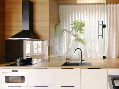 一間現代白色廚房，搭配木質牆面、黑色水龍頭與黑色排油煙機。