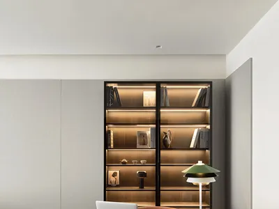 簡約辦公室空間，木質書桌上擺放筆記型電腦、檯燈與裝飾石，書桌後方有明亮照明