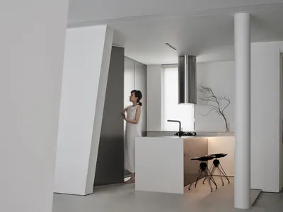 Modern, minimalist kitchen with white concrete surfaces, stainless steel appliances, and a sleek design.