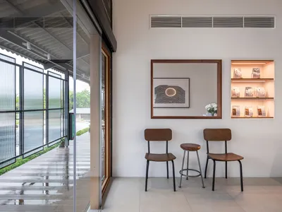 Two chairs and a vase create a cozy seating area in a showroom with a mirror and inviting ambiance