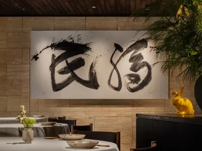 溫馨亞洲餐廳內部，設有餐桌、椅子、牆上藝術品與桌上的花瓶