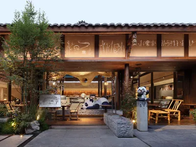 A warm and inviting Asian restaurant with wood and stone elements, comfortable seating, and lush greenery