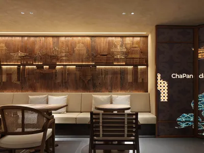 A warm and inviting interior design showroom featuring a large wooden wall with carvings, chairs, and dining tables