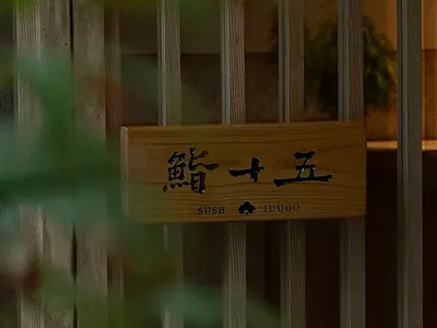 An Asian restaurant with wooden walls, a sign reading Sushi, and potted plants adding to the inviting and comfortable atmosphere