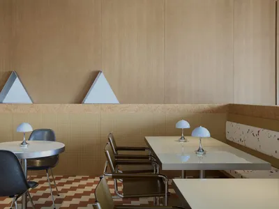 a dining area with a large table, chairs, lamps, and geometric patterns on the walls, creating a warm and inviting atmosphere