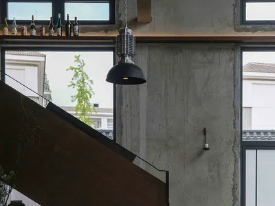 Modern restaurant interior with a black table, chairs, staircase, and potted plants