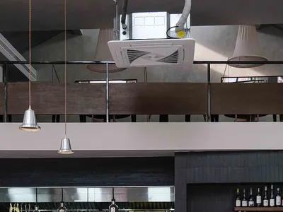 Modern restaurant interior with black walls, white elements, tables, chairs, kitchen appliances, and bottles of beverages