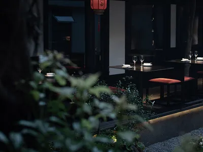 Modern restaurant interior with black walls, a red accent wall, and dining tables with wine glasses