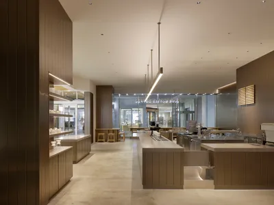 熱鬧的餐廳廚房，設有大型中島流理台，周圍環繞座椅，員工忙著服務顧客或準備食物