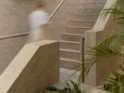 A modern hotel staircase with marble steps, surrounded by natural light and a sophisticated atmosphere
