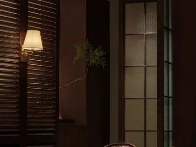 燈光昏暗的客廳，擺放兩張椅子與小桌，周圍環繞盆栽與一瓶物品，營造溫馨氛圍