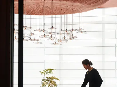 Sophisticated dining space with a large table, multiple chairs, wine glasses, cups, and bowls, set against a modern backdrop with a red ceiling