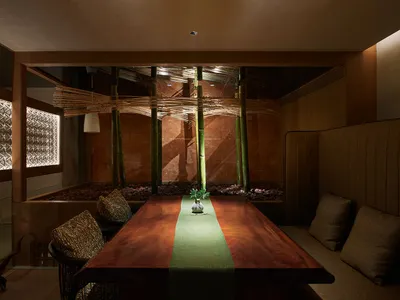 溫馨親切的亞洲餐廳內部，餐桌周圍環繞座椅，綠色桌巾上擺放盆栽與裝飾花瓶