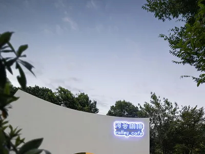 A modern Asian restaurant with a curved white building, large windows, and a dining area with chairs, located in a busy urban area