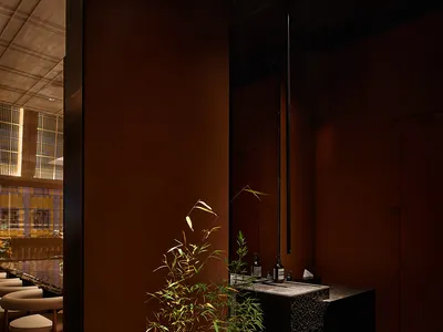 Modern restaurant interior with a black countertop, chairs, a potted plant, and a bottle, conveying a stylish atmosphere