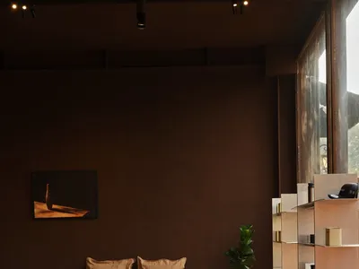 A warm and inviting interior design showroom with a brown wooden desk, two couches, and a bookshelf filled with books