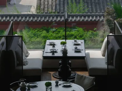 Cozy Asian restaurant with a large dining table, red wall, and tiled roof, set up for a meal