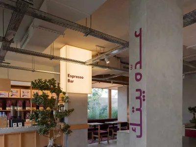 Inviting restaurant interior with Arabic writing on a wall, comfortable seating, and potted plants