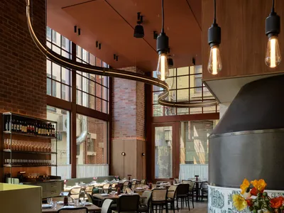 Warm dining space with wooden flooring, brick walls, and tables set with wine glasses, conveying a welcoming atmosphere for food and drink