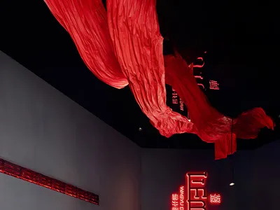 充滿活力的餐廳空間，配有多張餐桌、椅子、冰箱，以及牆上的紅色招牌