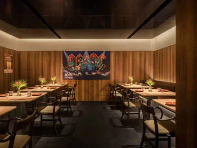 Dimly lit restaurant with wooden walls, tables, and chairs, creating a cozy atmosphere