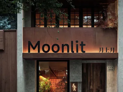 A modern Asian restaurant with a brown wooden facade, potted plants, and natural light from windows creating a bright and welcoming environment