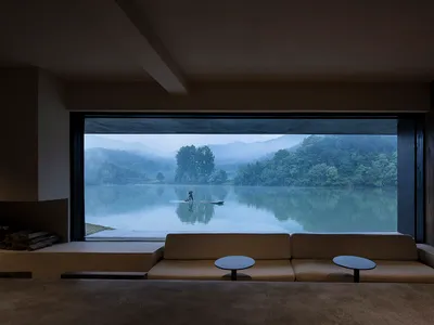 Cozy living space with a large couch, a window overlooking a serene lake, and a comfortable seating arrangement
