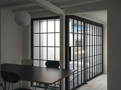 光線充足的餐廳空間，黑色餐桌周圍環繞座椅，左側牆邊有沙發