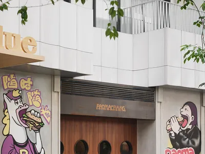 A modern Asian restaurant with a horse statue eating a sandwich, wood and concrete elements, and various artworks on the walls, creating a warm and inviting atmosphere