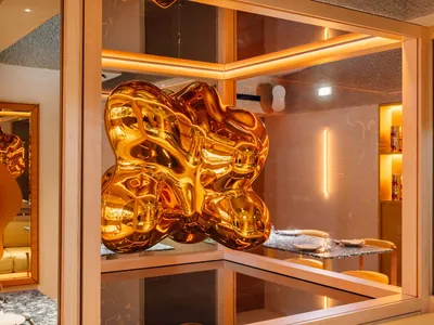 Elegant showroom with a gold metal sculpture, chairs, and decorative bottles, set against a sophisticated backdrop