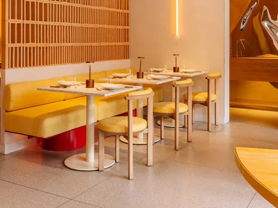 A well-lit dining area with a large yellow table surrounded by multiple chairs, creating a warm and inviting atmosphere