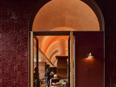 A cozy restaurant interior with red brick walls, several tables, and chairs, creating a warm and inviting atmosphere for patrons