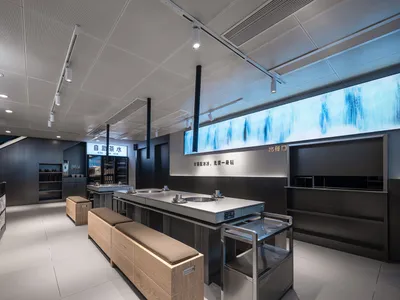 Clean and organized restaurant interior with a large counter, wooden benches, and bottles and cups on surfaces