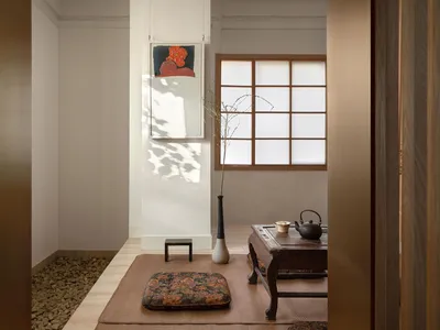 Cozy living space with hardwood floor, white walls, two couches, a chair, a vase, and a bowl, with a warm and inviting atmosphere