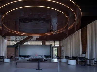 Elegant hotel lobby with a large circular table, multiple couches, and a wooden ceiling