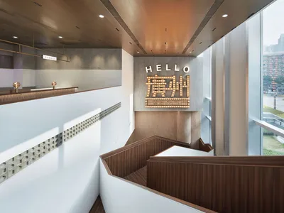 A modern staircase with wooden steps and a brown tint, featuring a large sign reading 'hello' above the steps in a welcoming atmosphere