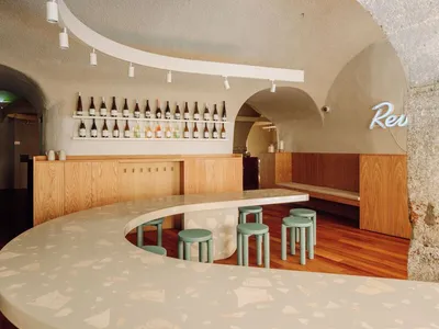 一家擁有弧形吧台、座椅與酒瓶的酒吧餐廳，營造出溫馨舒適的社交與用餐氛圍