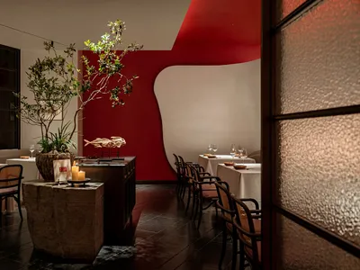 Cozy restaurant interior with red walls, white accents, and potted plants, creating a warm and inviting atmosphere